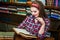 Clever female student girl sitting in library with books.