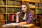 Clever female student with glasses girl sitting in library with books.