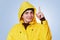 Clever handsome man raises fore finger as gets brilliant idea, wears yellow raincoat, has happy cheerful expression, isolated over