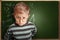 Clever pupil boy in eyeglasses near schoolboard