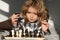 Clever thinking child. Clever concentrated and thinking kid playing chess. Kids brain development and logic game.