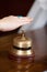 Client\'s Hand Over Bell At Hotel Reception