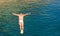 Cliff diver guy jumping in the blue sea from high rocks wall