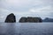 Cliff island in still sea. Unusual tropical seaside landscape with mountains in sea. Abandoned rocky islands