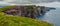 Cliff of Moher, county Clare, Ireland. Famous Irish tourist destination. Panorama image. Grey storm sky. Blue ocean and green gras