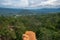 The cliff of orange soil mountain in the forest with cloudy sky view