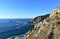 Cliff with path. Rocks and blue sea with foam, sunny day. Finisterre, Galicia, Spain.