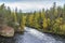 Cliff, stone wall, forest, waterfall and wild river view in autumn.