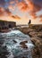 Cliffs in Kilkee at sunset, Ireland. Beautiful woman sitting on the edge of a cliff by the ocean