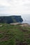 Cliffs of Moher on a cloudy day. Green fields and calm water. Ireland,