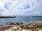 Clifftop view of the cove at cale santandria in menorca with rocky shore and blue summer sea with white clouds