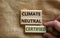 Climate neutral certified symbol. Wooden blocks with words `Climate neutral certified`. Male hand. Beautiful canvas background,