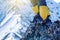 Climber in crampons stands on the rocks in front of the entrance to the peak on the background of the snowy mountains.