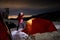 Climber with headlamp near orange tent at night