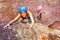 Climber in helmet reaching top of the mountains