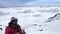 A climber in a helmet and sunglasses stands above the clouds on his way to the top of the mountain