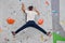 Climber man hanging in a twine on a climbing wall bouldering the wall, inside on colored hooks