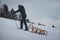 Climber pulls to the top of a wooden sled to ride on the piste. Pause for rest. Candid portrait of a man pulling a sledge, which