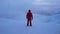 A climber in a red suit stands on top of mountain