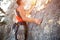 A climber in a red t-shirt climbs a gray rock. A strong hand grabbed the lead, selective focus. Strength and endurance, climbing e