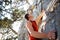 A climber in a red t-shirt climbs a gray rock. A strong hand grabbed the lead, selective focus. Strength and endurance, climbing e
