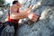 A climber in a red t-shirt climbs a gray rock. A strong hand grabbed the lead, selective focus. Strength and endurance, climbing e