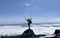 A climber with trekking poles is standing on the top of a volcano. Mountain climbing