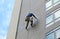 Climber worker hanging on ropes to repair building service on high rise building
