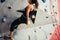 Climber young woman climbing on practical wall indoor, bouldering, recreation, sport