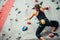 Climber young woman climbing on practical wall indoor, bouldering, recreation, sport