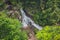 Climbers go down a cliff near a waterfall