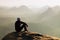 Climbing adult man at the top of rock with beautiful aerial view of the deep misty valley bellow