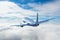 Climbing aircraft flies low above a layer of clouds