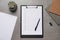 Clipboard with checkboxes, plant and office stationery on grey table, flat lay. Checklist