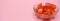 Clipped to banner size image of chopped tomato in a glass bowl isolated on a pink background