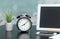 Clock with alarm clock and home plant in a pot, Tablet computert, notebook, phone on the table.