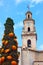 Clock and Bells Tower with umbrellas decorated cypress tree