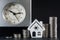 Clock, columns of coins and the contour of the house. Savings concept