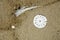 Clock face on beach sand and feather