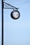 Clock on an iron pillar against a blue sky.