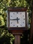 Clock situated on a city street with trees in the background