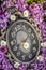 Clock surrounded by spring flowers. Shallow depth of field with selective focus on clock. Lilac flowers