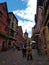 Clock tower and traditional Houses with colorful facades and sloping roofs in Riquewihr, France.