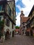 Clock tower and traditional Houses with colorful facades and sloping roofs in Riquewihr, France.