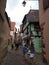 Clock tower and traditional Houses with colorful facades and sloping roofs in Riquewihr, France.