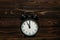 Clock on a wooden background. The clock shows the time of eleven o`clock in the afternoon. The clock shows the time of eleven o`
