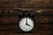 Clock on a wooden background. The clock shows the time of four o`clock in the afternoon. The clock shows the time four o`clock i