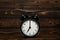 Clock on a wooden background. The clock shows the time of seven o`clock in the afternoon. The clock shows the time seven o`clock