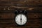 Clock on a wooden background. The clock shows the time of six o`clock in the afternoon. The clock shows the time six o`clock in