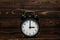 Clock on a wooden background. The clock shows the time of three o`clock in the afternoon. The clock shows the time of three o`